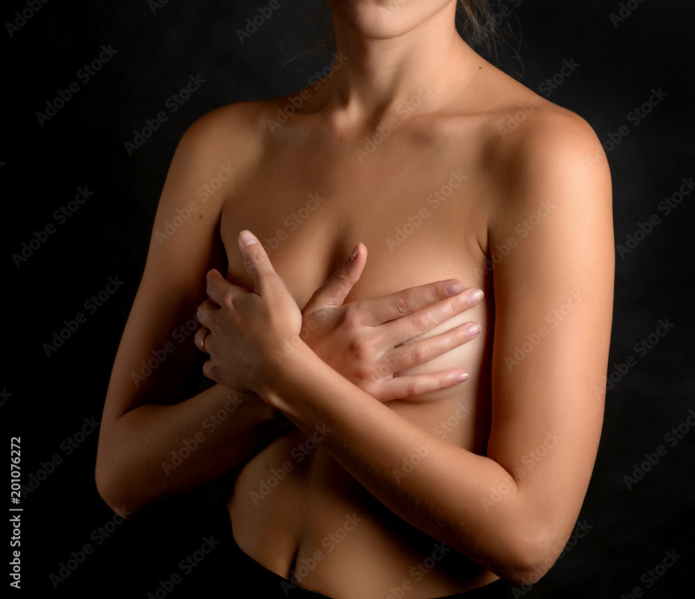 Woman covering her breast on dark background.