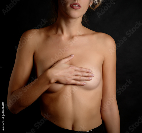 Woman covering her breast on dark background.