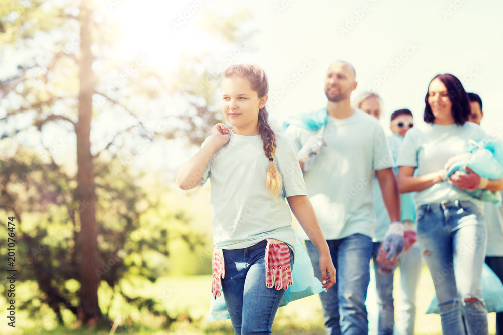 volunteering, charity, cleaning, people and ecology concept - group of happy volunteers with garbage bags walking in park volunteering, charity, cleaning, people and ecology concept - group of happy volunteers with garbage bags walking in park