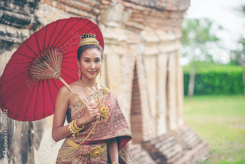 Beautiful asian women in traditional Thai dress with antique red umbrella . Beauty fantasy Thai woman. Beautiful Thai girl in traditional dress costume, Ang Thong province, Thailand.