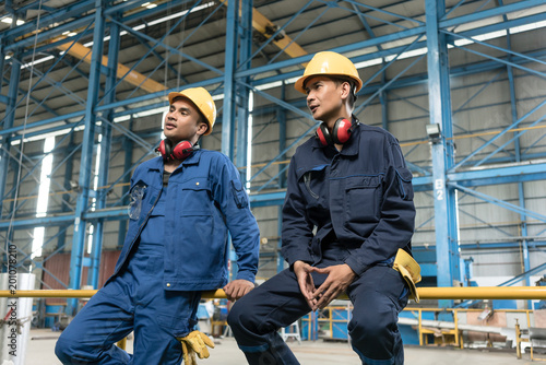 Fotografie Rear view of two blue-collar workers during break in the interior of an industri