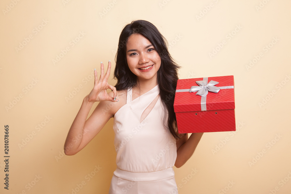 Young Asian woman show OK with a gift box. Young Asian woman show OK with a gift box.