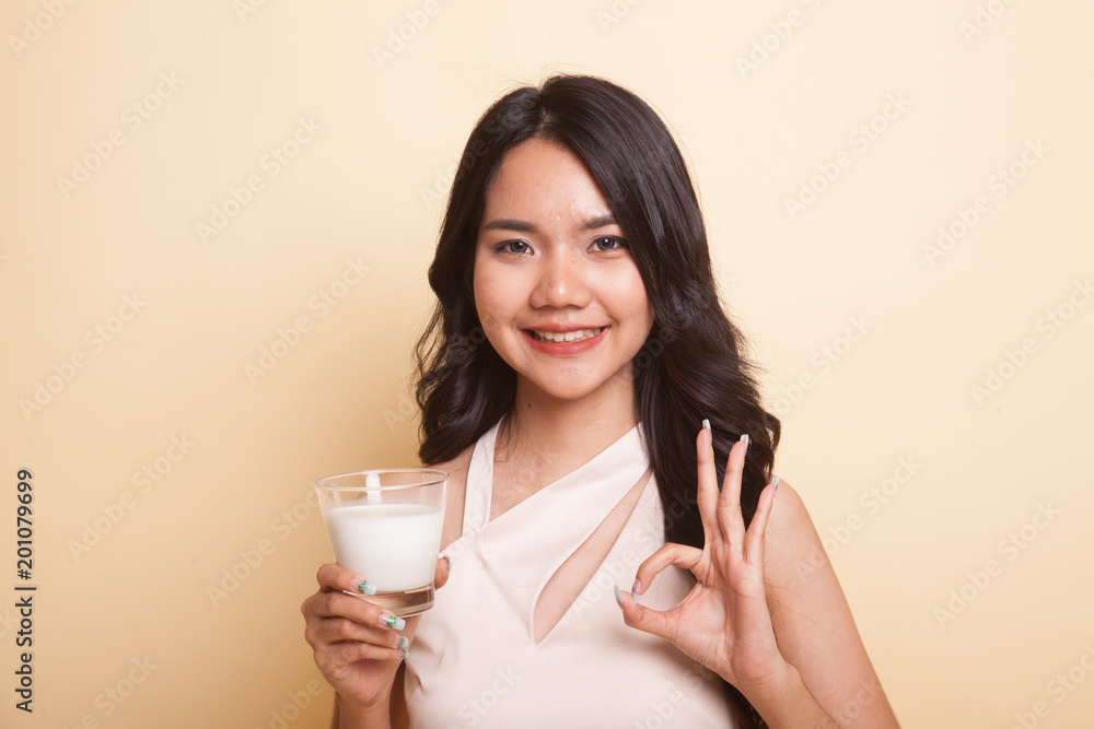 Healthy Asian woman drinking a glass of milk show OK sign. Healthy Asian woman drinking a glass of milk show OK sign.