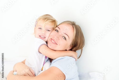 Portraits of Happy and loving mother embracing her daughter on the bed. Family morning concept. Spending free time together at home. Soft selective focus. Space for text.