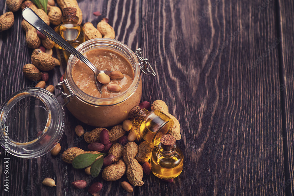 Natural peanut butter with oil in a glass jar and peanuts Natural peanut butter with oil in a glass jar and peanuts