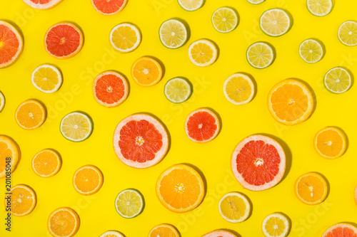 Flat lay colorful summer background. Different citrus fruits on yellow background close up. Top view lemon, lime, orange and grapefruit on yellow background