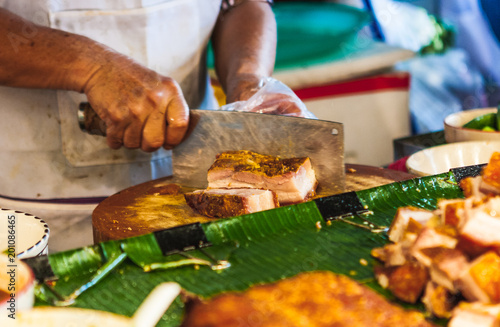 Butcher chopping meat at street food stall at the Chatuchak weekend market, Bangkok, Thailand