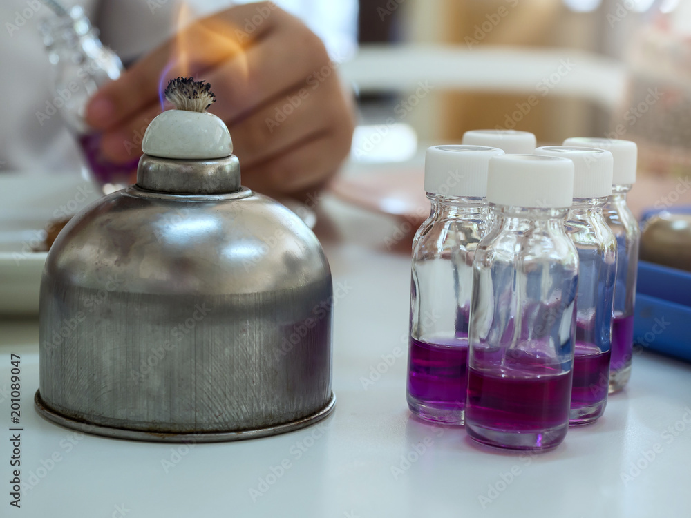 Close-up of bottle being sterilized with an alcohol burner before use in bacterial cultures. Medicine and microbiology concept. Close-up of bottle being sterilized with an alcohol burner before use in bacterial cultures. Medicine and microbiology concept.