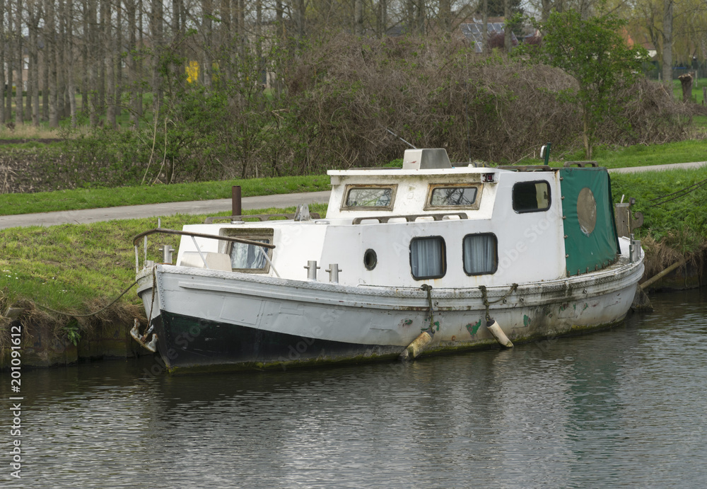 White boat with green hood along the waterfront White boat with green hood along the waterfront