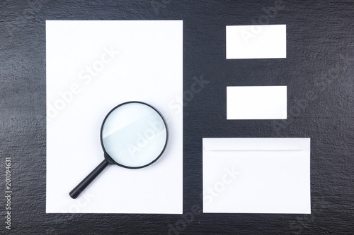 Business card. Corporate stationery set mockup. Blank textured brand ID elements on wooden table. Magnifier. Top view.