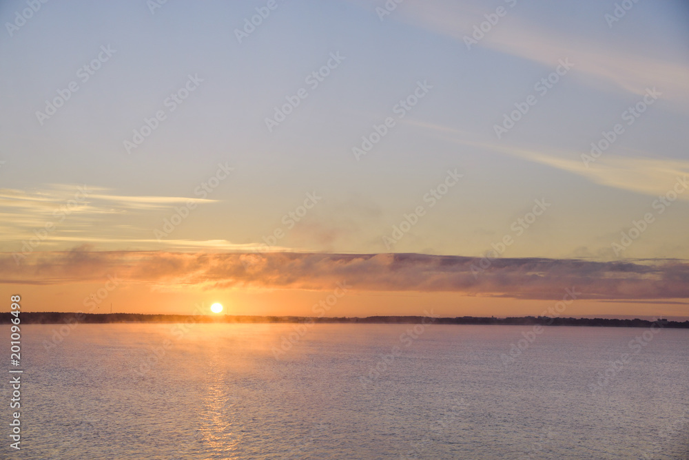 Golden, colorful, abstract sea sunrise view at horizon, vibrant sky landscape and small waves in the water. 