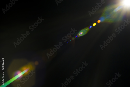 Solar camera lens flare light create hexagon of objective iris shapes of different colors depending on used antireflection coating of each lens surface on dark black background photo