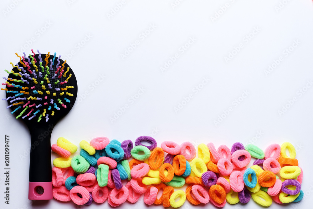 Colorful comb with bright multi-colored elastic bands for hair on a white background.Copy space.