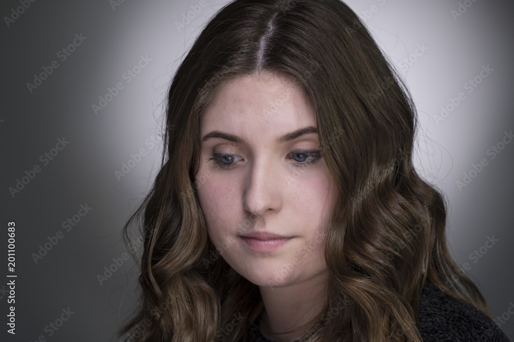 Portrait of a young woman with long brown hair, looking down and away from camera Portrait of a young woman with long brown hair, looking down and away from camera