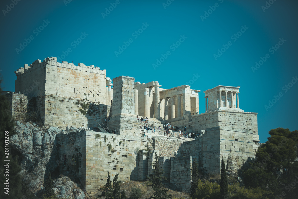 Ruins of ancient acropolis athens surrounded by park or forest. Old building with columns on high platform made out of bricks, sky background. Cultural and architectural heritage concept.
