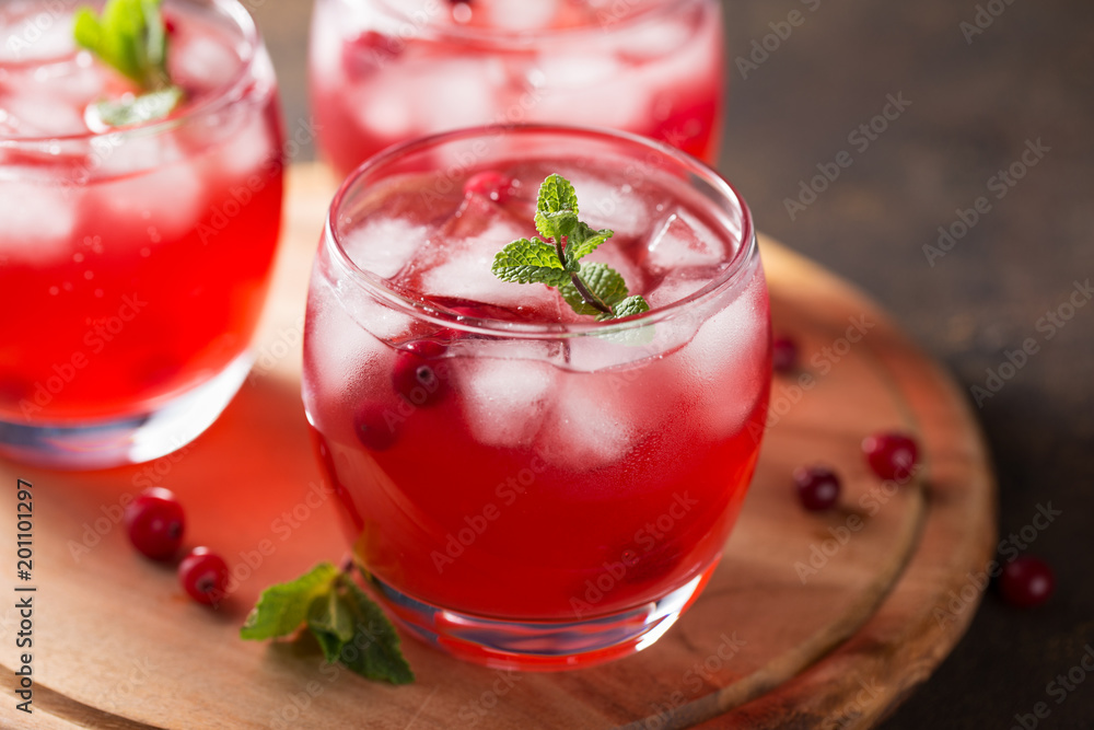 Summer cold beverage with cranberry, ice cubes, mint on the wooden cutting board. Summer cold beverage with cranberry, ice cubes, mint on the wooden cutting board.