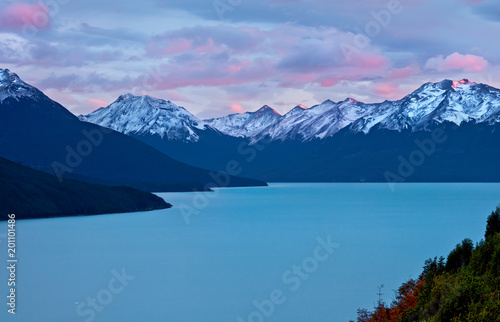 Argentinian lake (Lago Argentino) at sunset, snow covered mountains and beautiful pink clouds at background. © Valeriy
