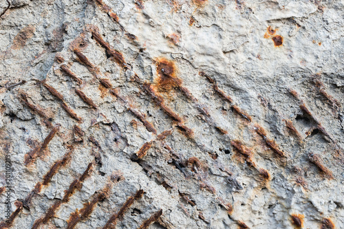Textured background of an old concrete wall with a rusty outwardly extending reinforced armature. Close-up. Grunge background