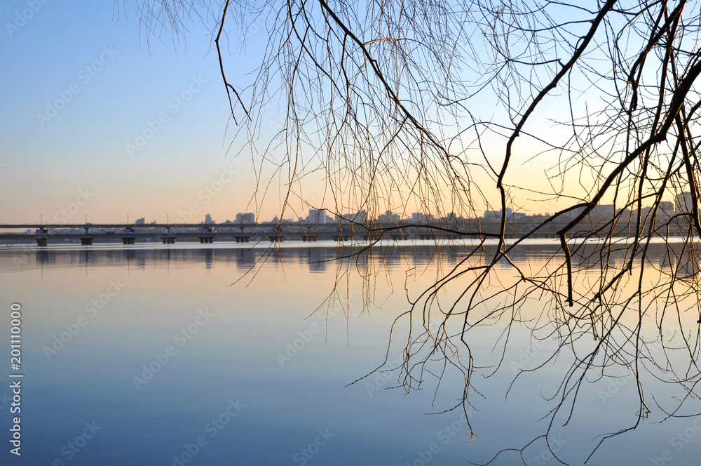 Sunset against the background of a river and branches of trees Sunset against the background of a river and branches of trees