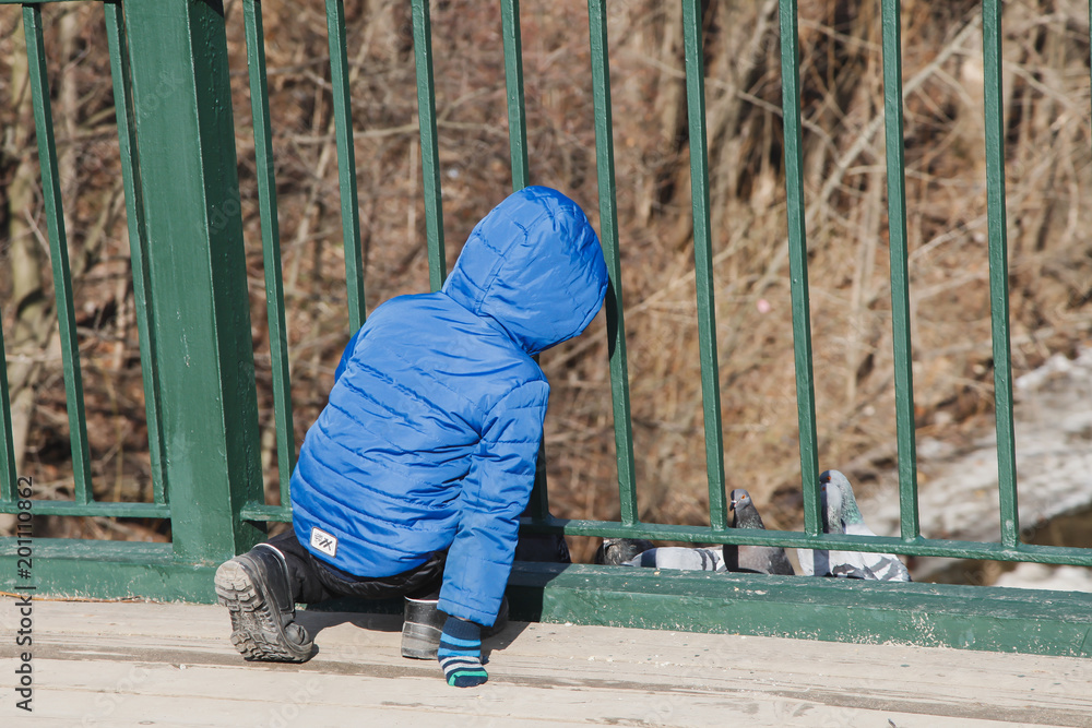 little boy squatting with his back turned looking through the bars little boy squatting with his back turned looking through the bars