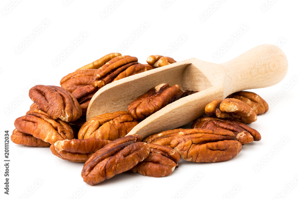 Pile of peeled pecans and wooden spoon on a white, isolated.