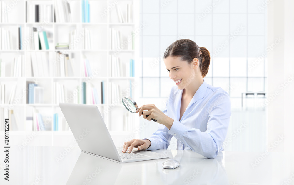 Business smiling woman or a clerk working at her office desk with computer and magnifying glass, search concept Business smiling woman or a clerk working at her office desk with computer and magnifying glass, search concept