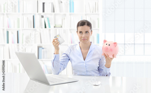 Obraz na plátně displeased woman at the computer with credit card and piggy bank, overdraft limi