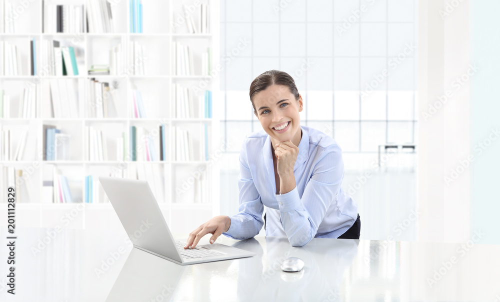 Business smiling woman or a clerk working at her office desk with computer, looking in camera, career and success concept Business smiling woman or a clerk working at her office desk with computer, looking in camera, career and success concept