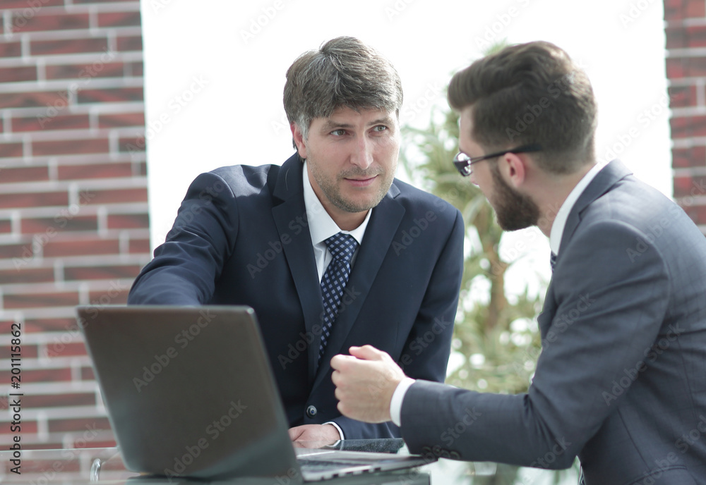 Two businessmen working together using laptop on business meeting in office Two businessmen working together using laptop on business meeting in office