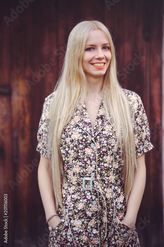 Beautiful young woman in doted summer dress on red old wooden background, looking at camera. rustic style, pretty