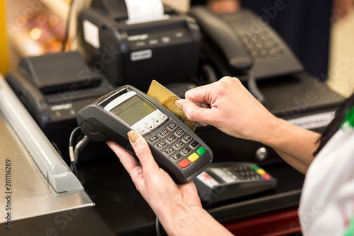Woman hand with credit card swipe through terminal for sale, in market. Shopping and retail concept