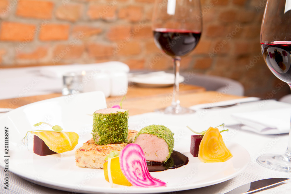Roast pork tenderloin with crispy potato bread, marinated beetroots and green pepper sauce served in a restaurant