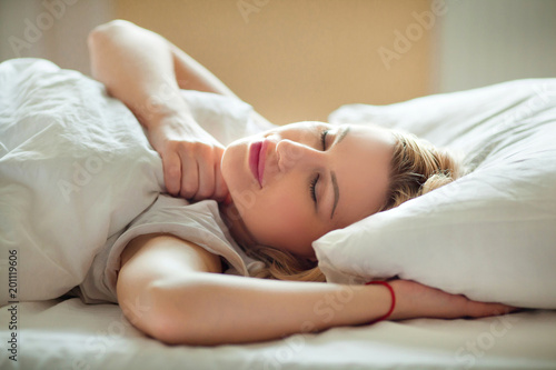 beautiful young sleeping girl in a white bed in the morning indoors