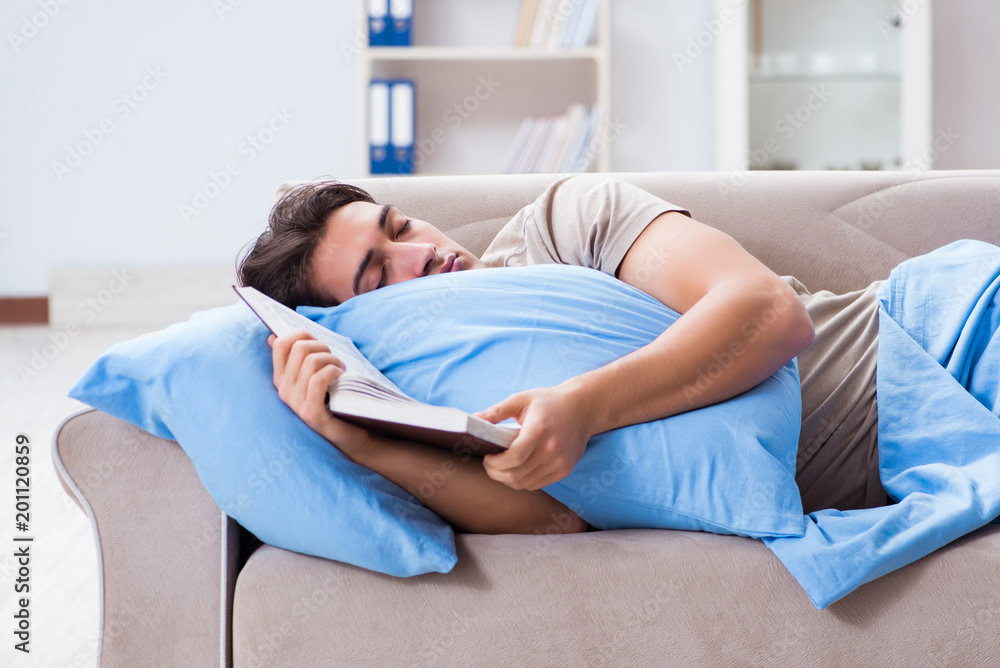 Young student man preparing for college exams in bed with book Young student man preparing for college exams in bed with book
