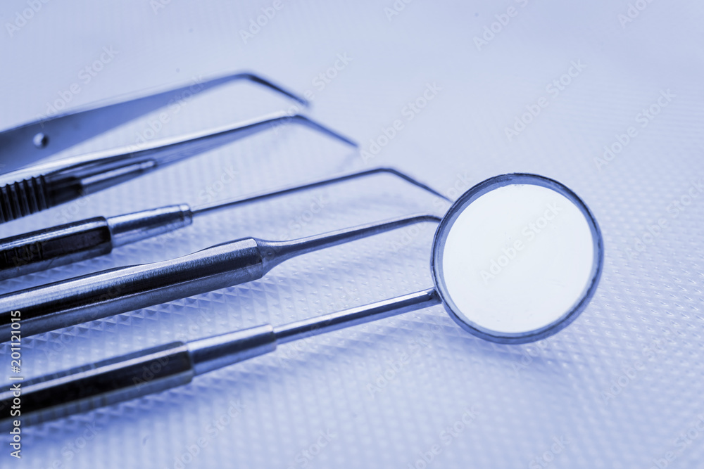 Steel dental instruments, mirror, on a blue background. Stomatology Steel dental instruments, mirror, on a blue background. Stomatology
