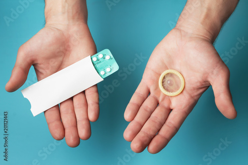 Photos Male contraceptives. Pills and condom in hands of men
