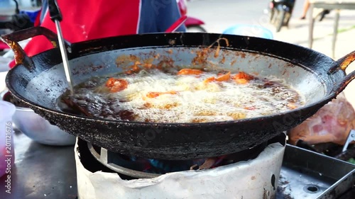 Chicken drummets deep frying in oil in a cast iron frying pan photo