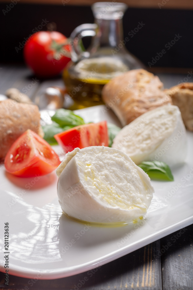 Traditional italian food - white ball mozzarella buffalo Italian soft cheese with cheese knife, tomato, basil, olive oil Traditional italian food - white ball mozzarella buffalo Italian soft cheese with cheese knife, tomato, basil, olive oil