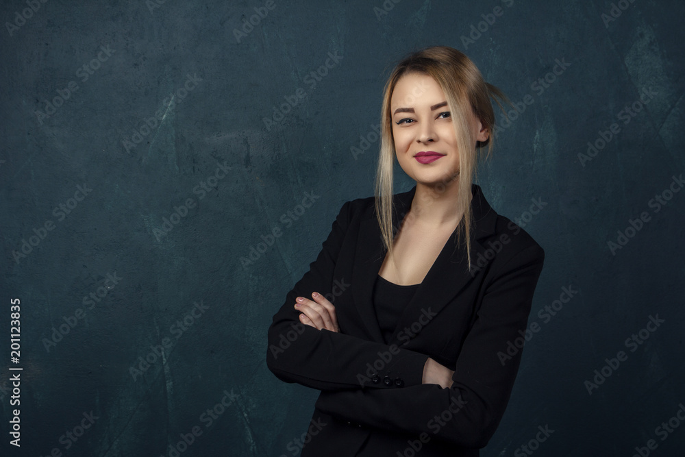 Close-up portrait with lots of details, beautiful smiling woman in black suit against a blue textural wall background with place for text. Close-up portrait with lots of details, beautiful smiling woman in black suit against a blue textural wall background with place for text.
