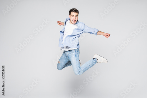 Full-length photo of funny man in casual t-shirt and jeans running or jumping in air isolated over white background