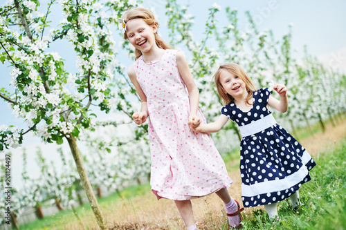 Two little girl run and having fun in spring garden