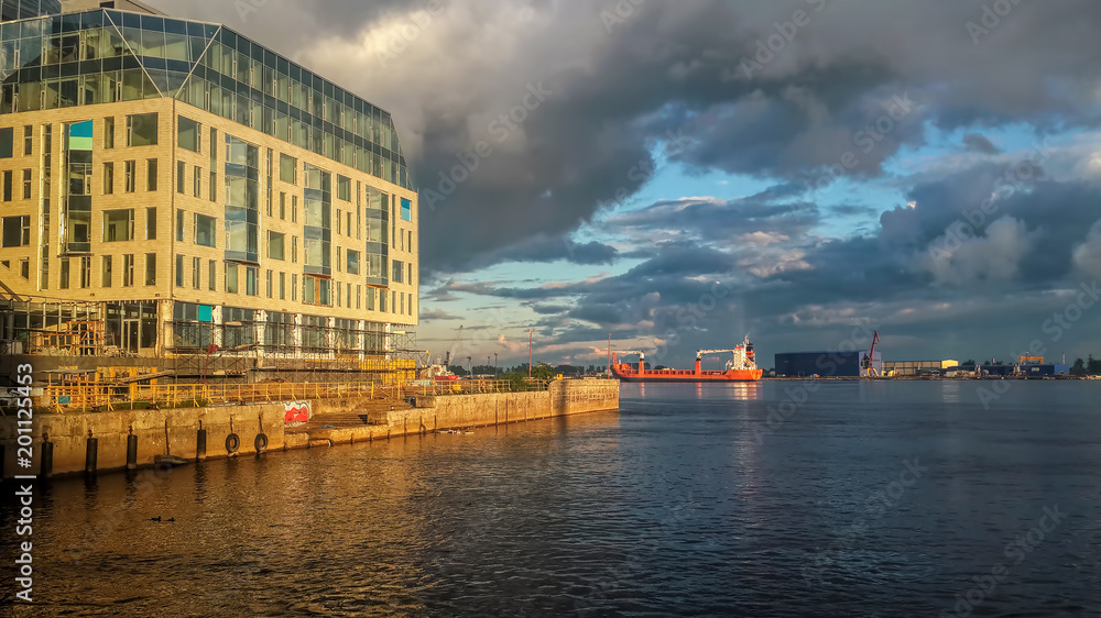 Late afternoon landscape. The skyline glows under an orange sunset light. The ship is moving along the river Late afternoon landscape. The skyline glows under an orange sunset light. The ship is moving along the river