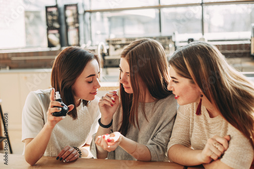 Three young women friends smelling new perfume photo