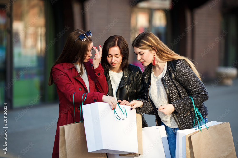 Young girls look into paper bag near shopping mall Young girls look into paper bag near shopping mall