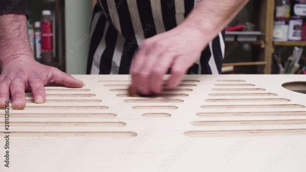 Close up man's hands polishing plywood furniture detail with sandpaper. Handicraft production of furniture. Close up man's hands polishing plywood furniture detail with sandpaper. Handicraft production of furniture.