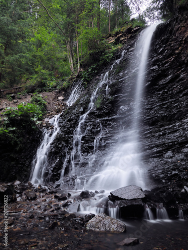 Waterfall at the carpatian mountains at the green rainy pine forest