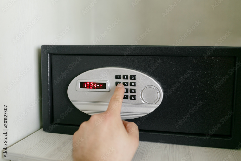 easy password. Hand press key on black safety box in hotel room. Concept safe storage of money and documents easy password. Hand press key on black safety box in hotel room. Concept safe storage of money and documents