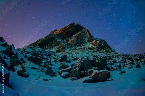 Beautiful outdoor view of milky way with thousand of stars in the sky and huge mountain covered with snow in snowy winter in the Arctic Circle photo