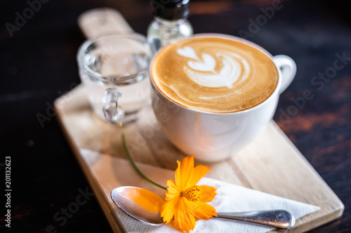 cappucchino coffee, cup of water and syrup on wooden table