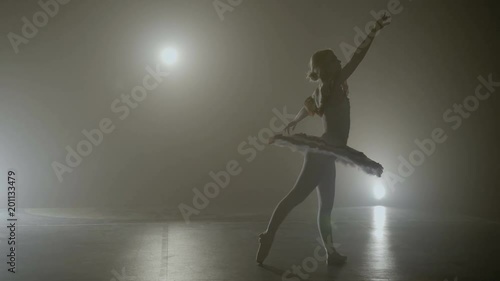 Young teenager ballerina wearing pointe shoes making pirouettes while getting ready for the show on a foggy stage